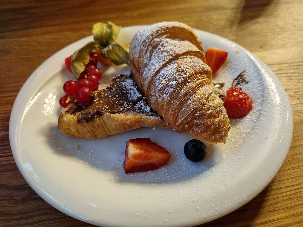 A golden, flaky croissant dusted with powdered sugar