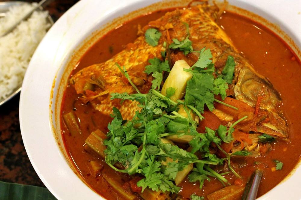A plate of fish head curry with vegetables served in a curry gravy