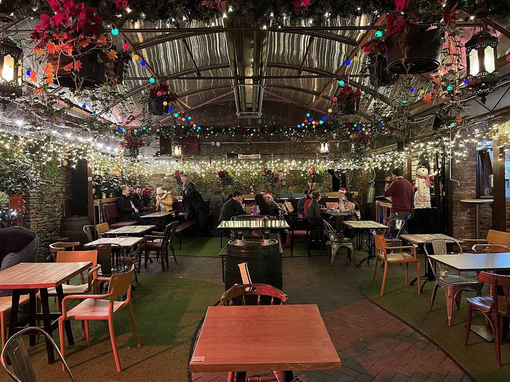 A covered pub beer garden with tables, chairs and string lights
