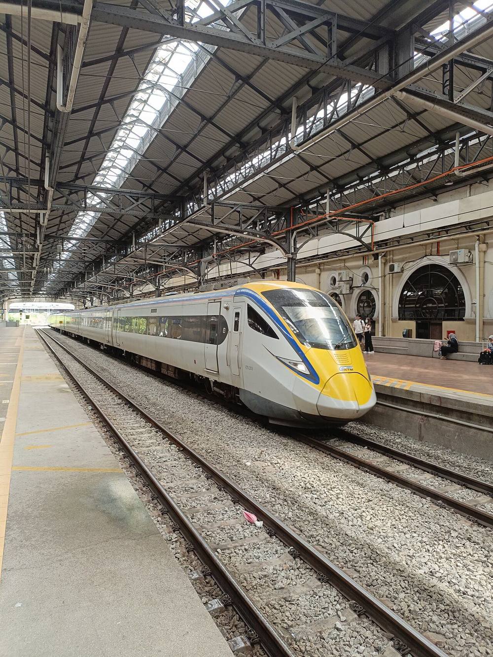 A KTM ETS electric train arriving under the arched roof of a station in Kuala Lumpur
