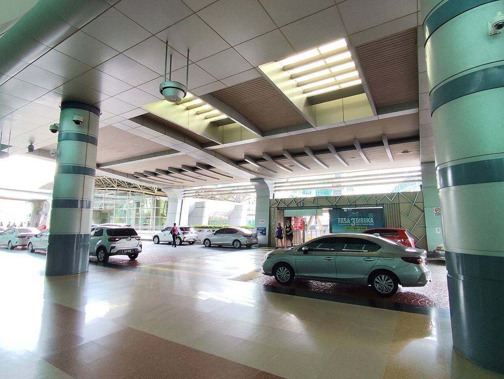 A car pick-up point at JB Sentral station in Johor Bahru, with cars waiting on the driveway