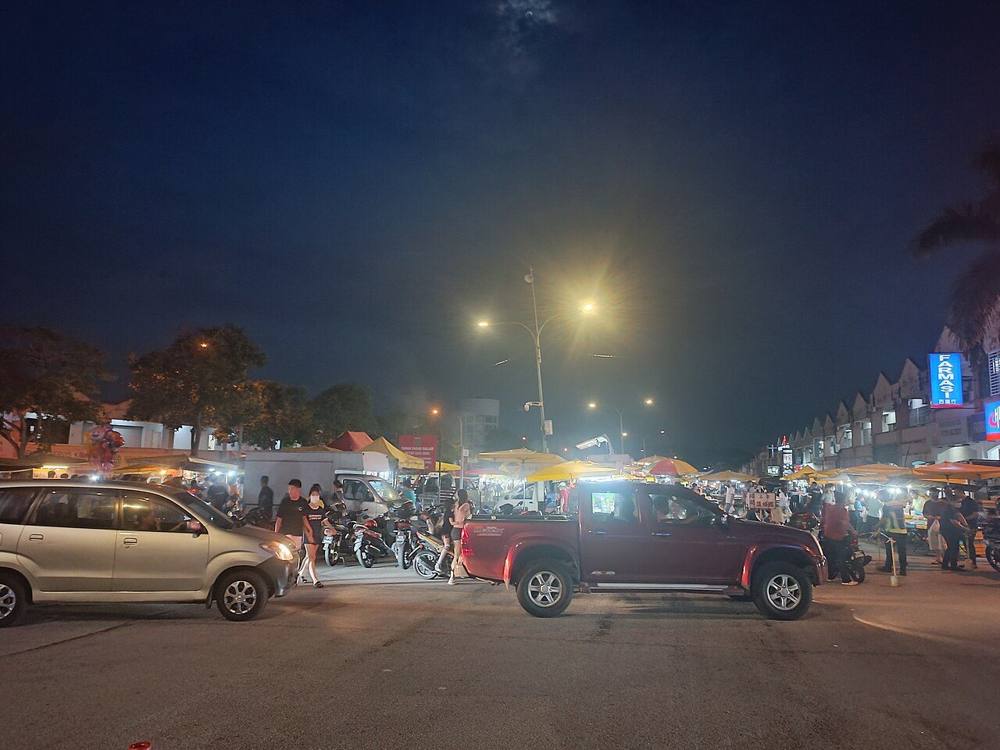 A Malaysian pasar malam at night with stalls and shoppers along the roadside