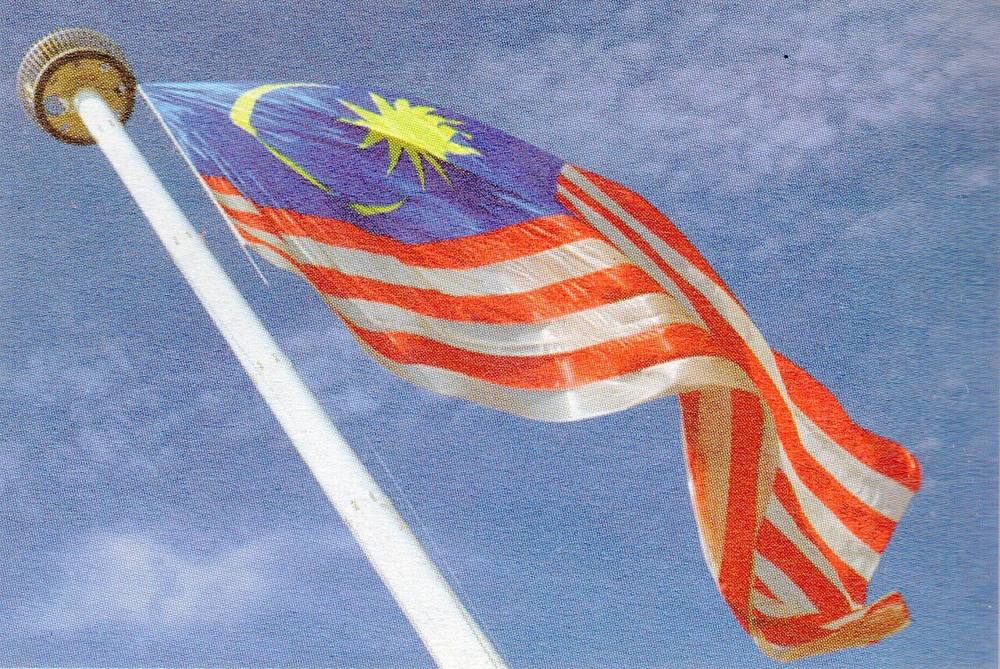 The Malaysian flag, the Jalur Gemilang, flying from a white flagpole against a blue sky