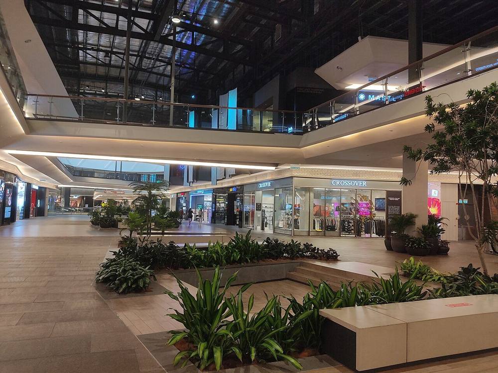 A spacious shopping mall atrium at Mid Valley Southkey with planters, shopfronts and upper-level walkways