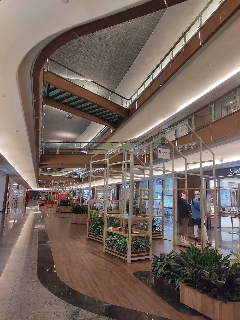 A multi-level mall interior at Mid Valley Southkey with curved balconies, a wooden floor display area and shops
