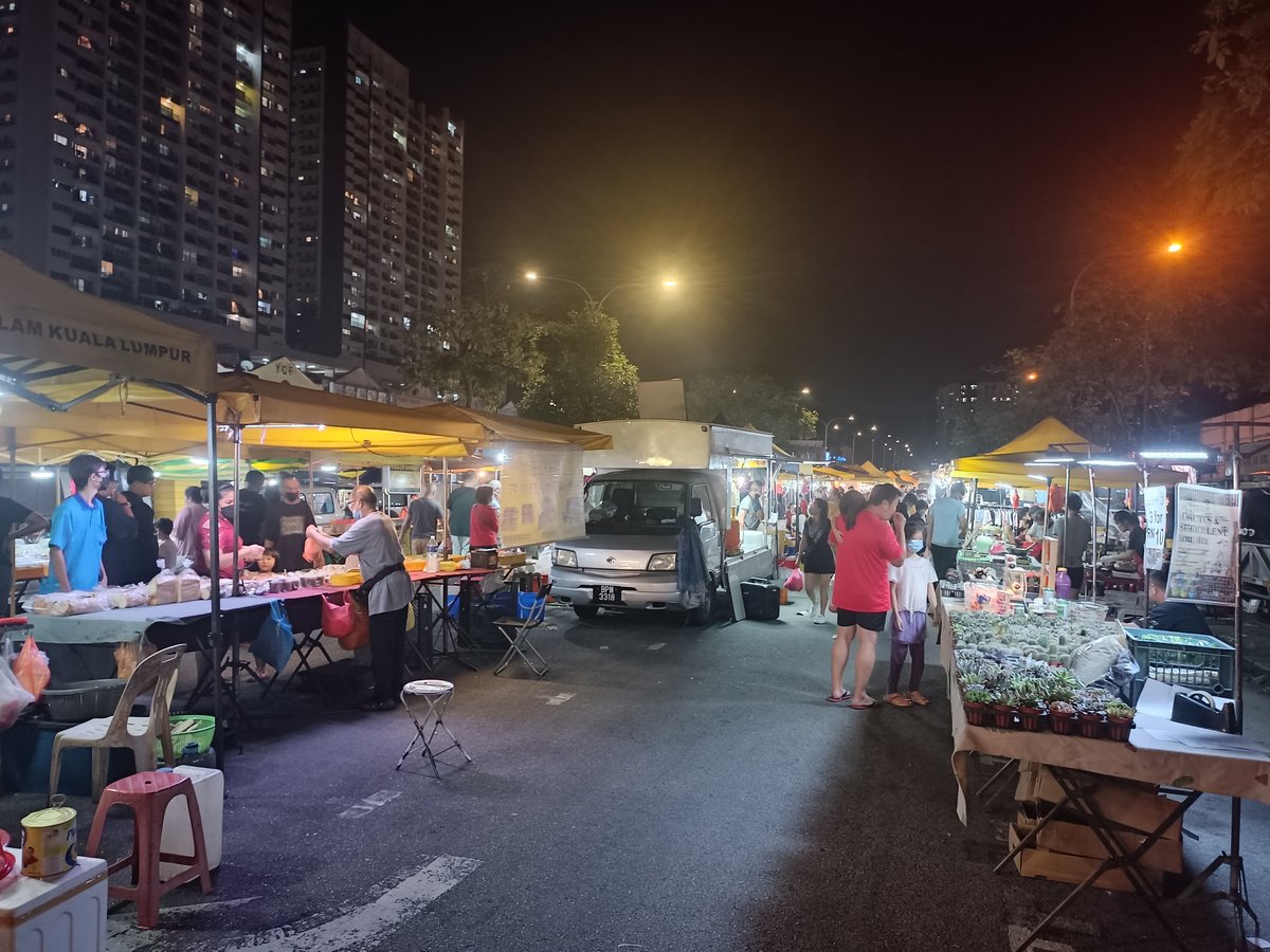 Rows of pasar malam stalls lit up along a Malaysian street at dusk