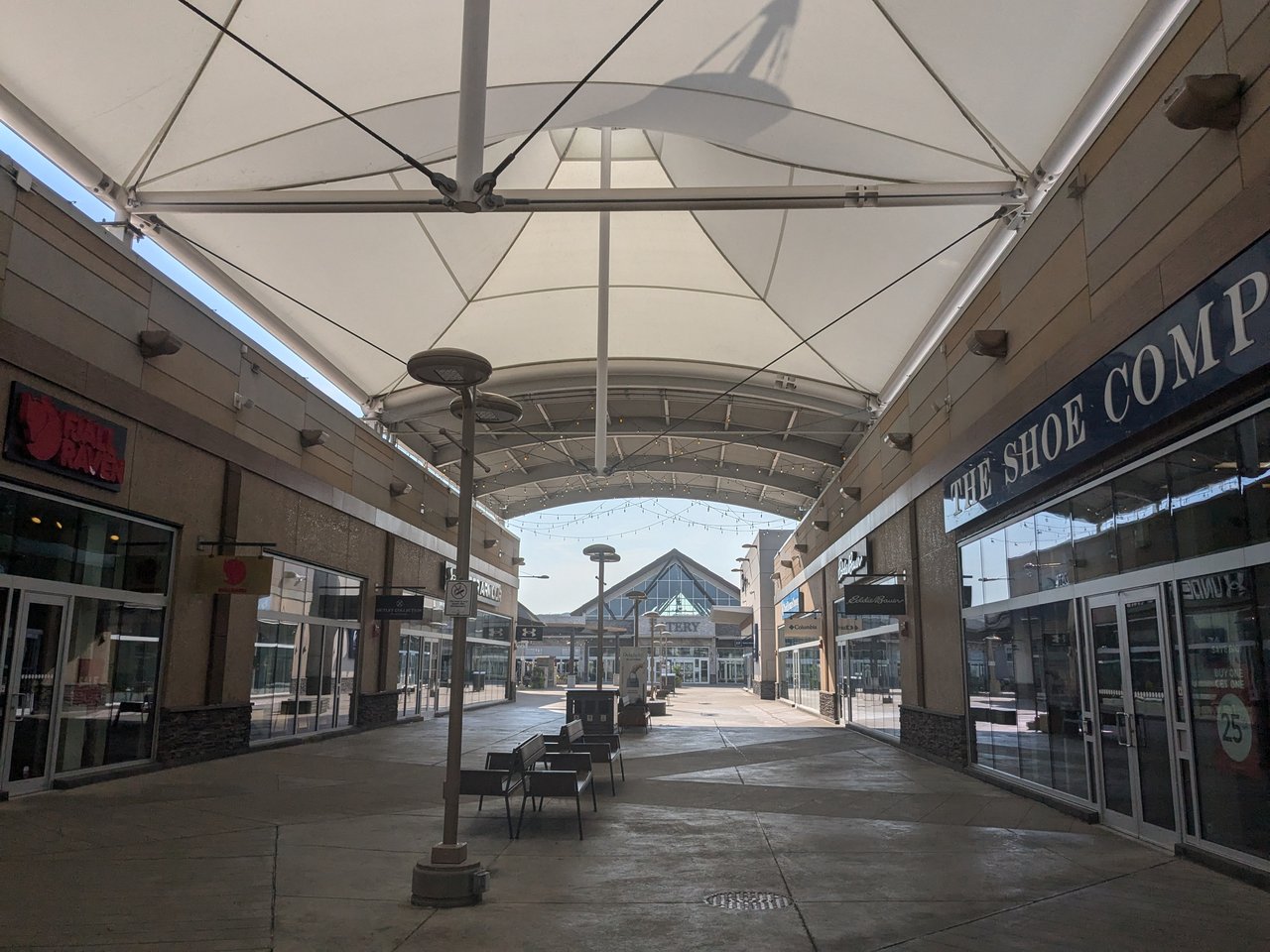 Open-air outlet mall with shoppers walking past storefronts