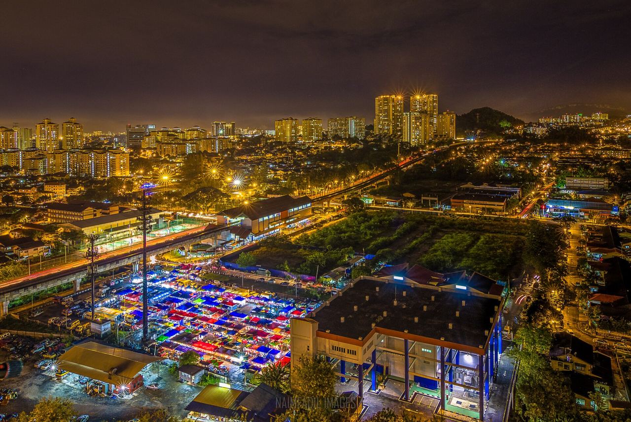 Rows of pasar malam stalls lit up along a Malaysian street at dusk