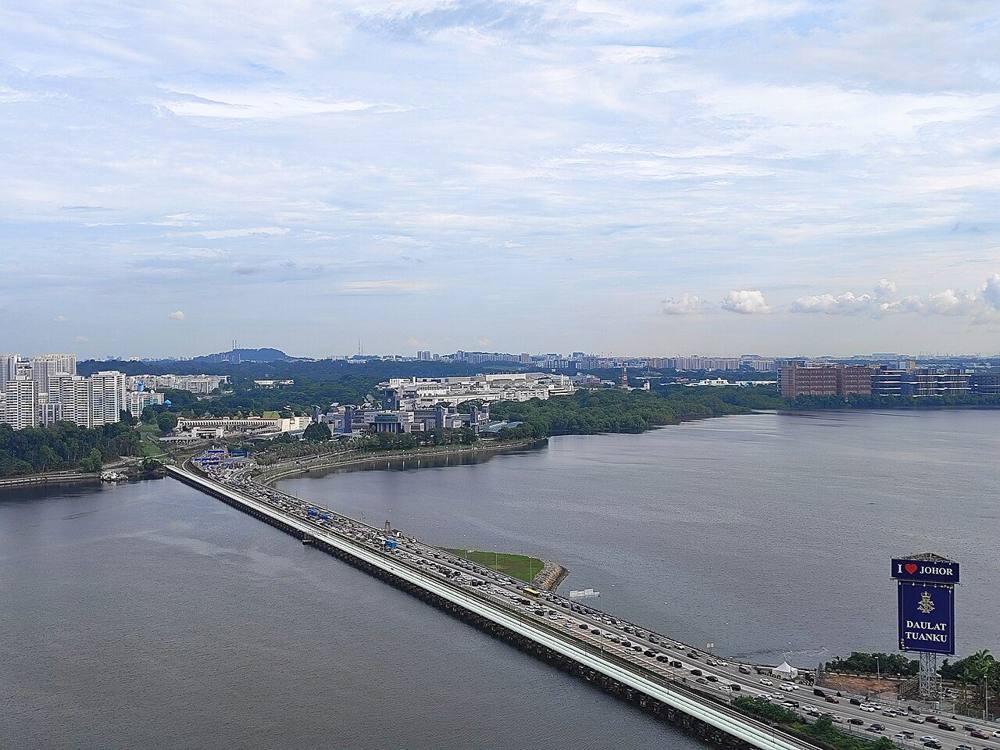 Aerial view of the Johor-Singapore Causeway, with a long line of vehicles crossing towards Johor Bahru