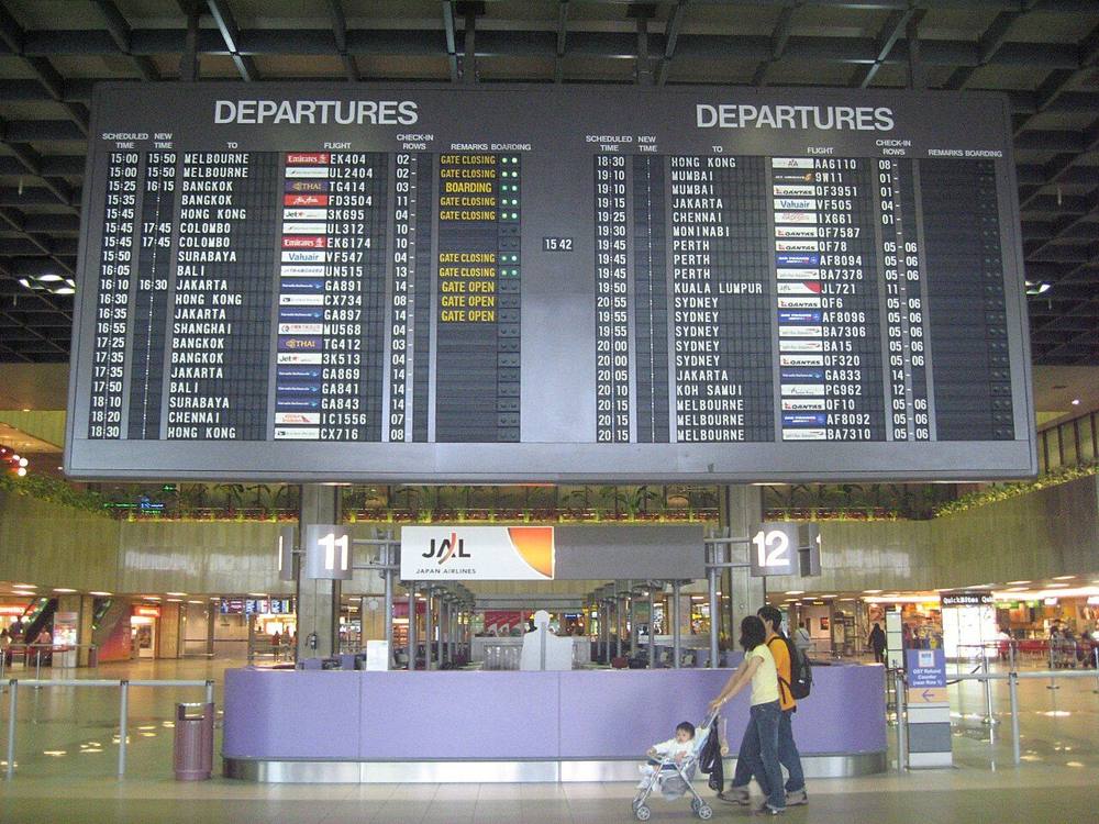 The departures hall at Singapore Changi Airport Terminal 1 with a large flight information board