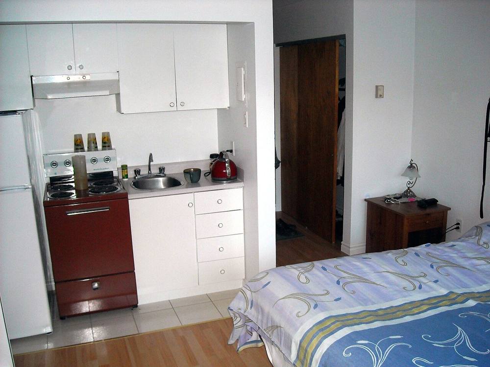 A small studio-style room with a kitchenette beside the bed, shown as a generic example