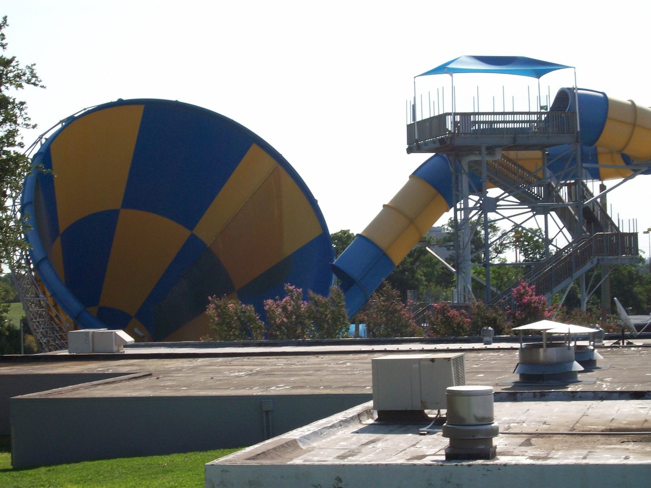 Tornado funnel water slide at a theme park with riders descending into the bowl